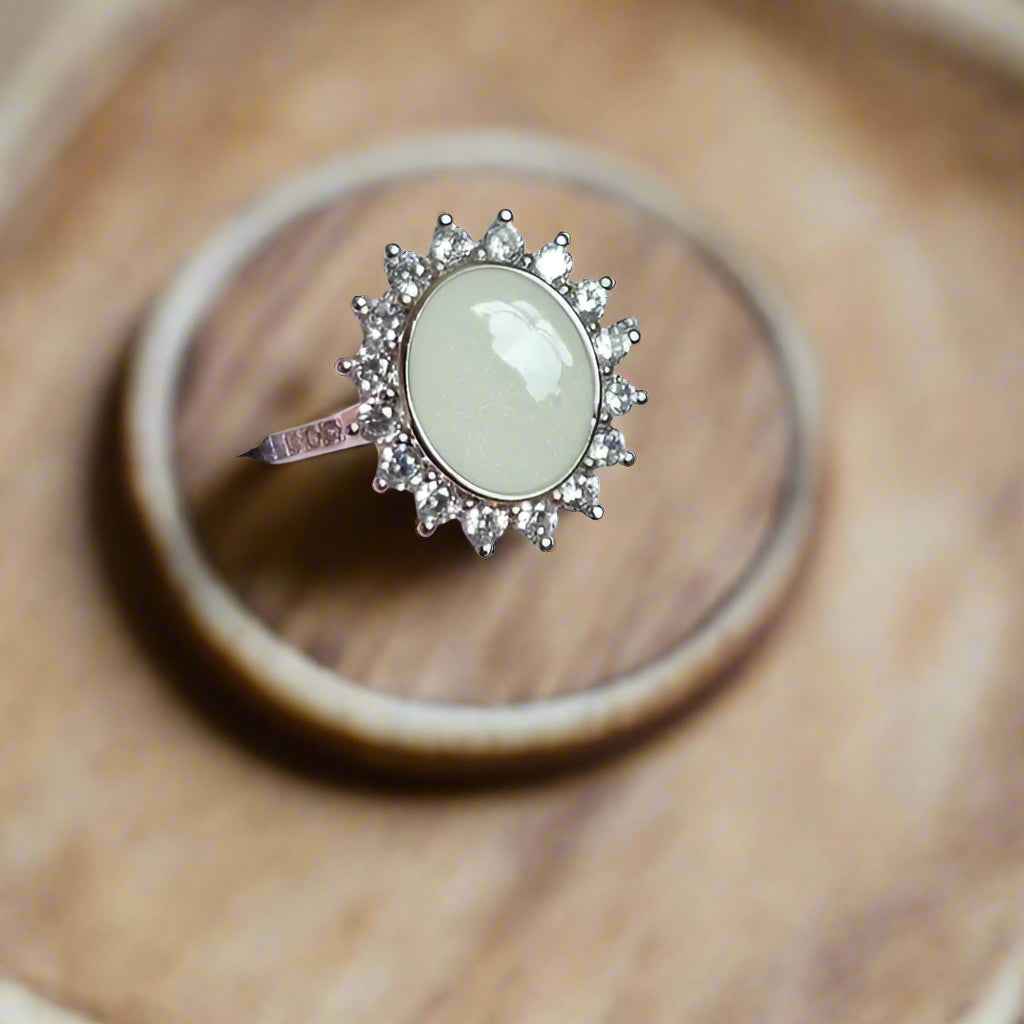 Silver ring with a light-colored stone in a pink box
